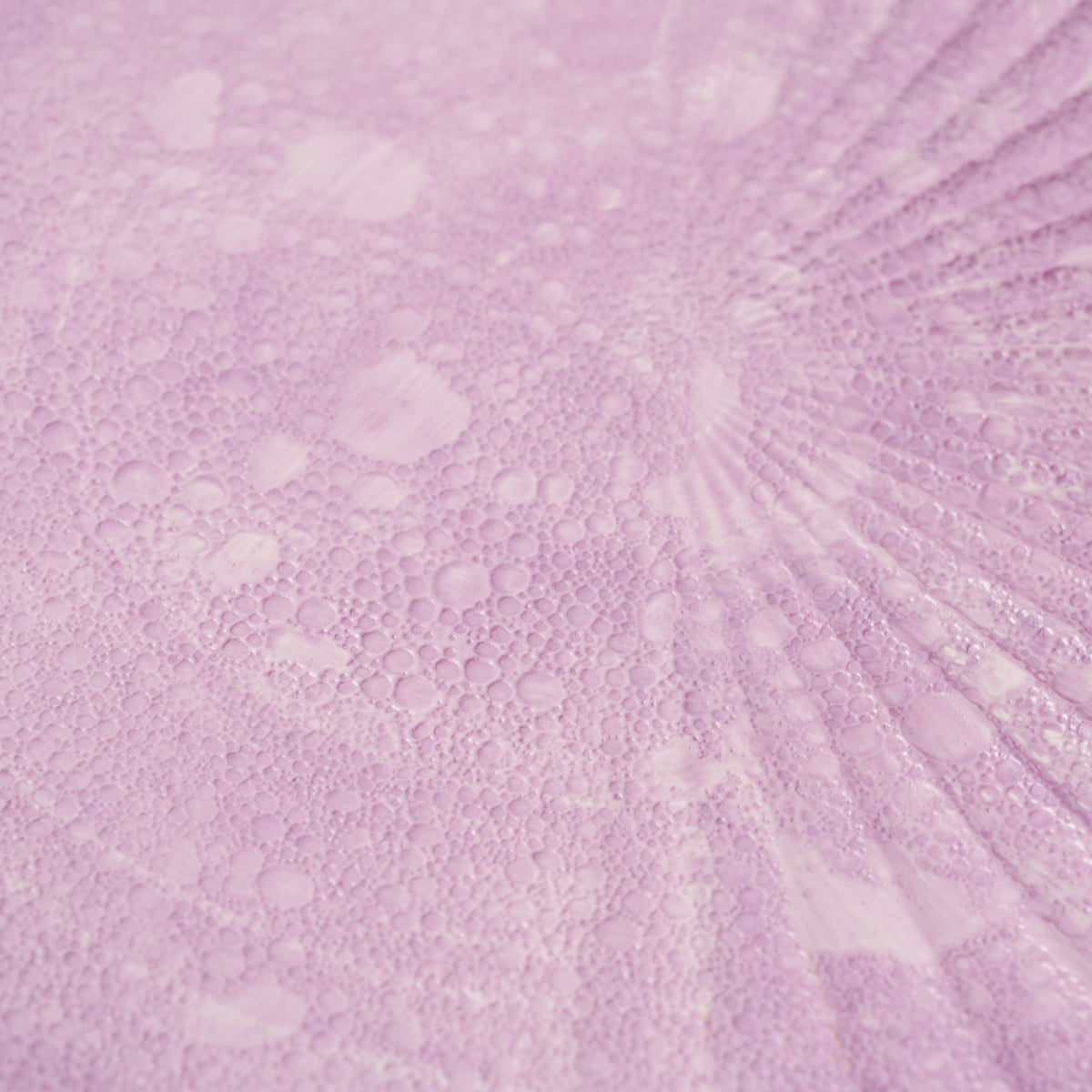 Detailed view of pink bubble glass plate with scalloped edge, emphasizing textured surface and soft pink hue