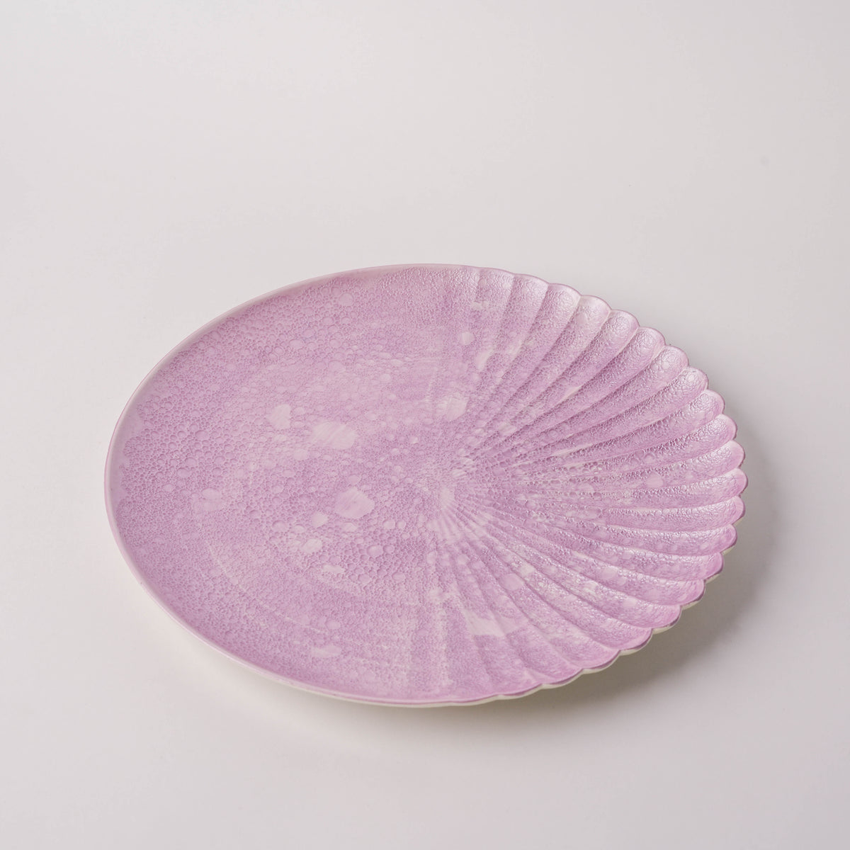 Pink glass plate with bubble texture and scalloped edge, close-up view showing detailed pattern and soft color