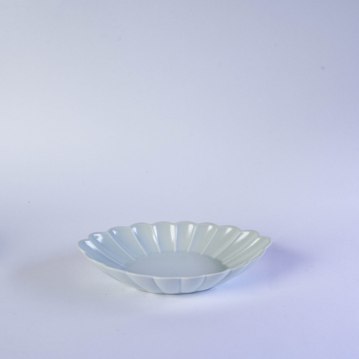 Colorful ceramic oval plates in white, yellow, green, and orange with carved chrysanthemum pattern, ideal for table presentation