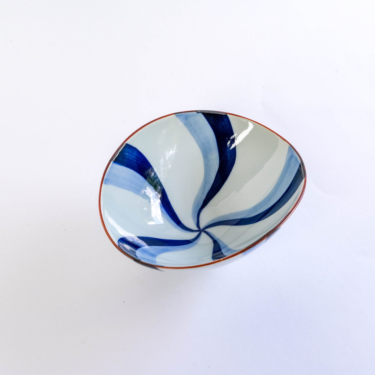 Close-up of the blue and white painted ceramic bowl with flowing water design, oval shape, on a white background