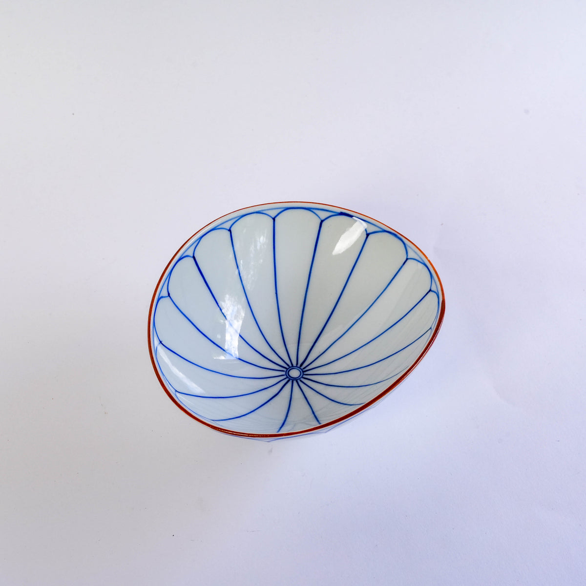 Close-up of the blue floral pattern on the white porcelain oval bowl with orange rim, Japanese style, for serving food