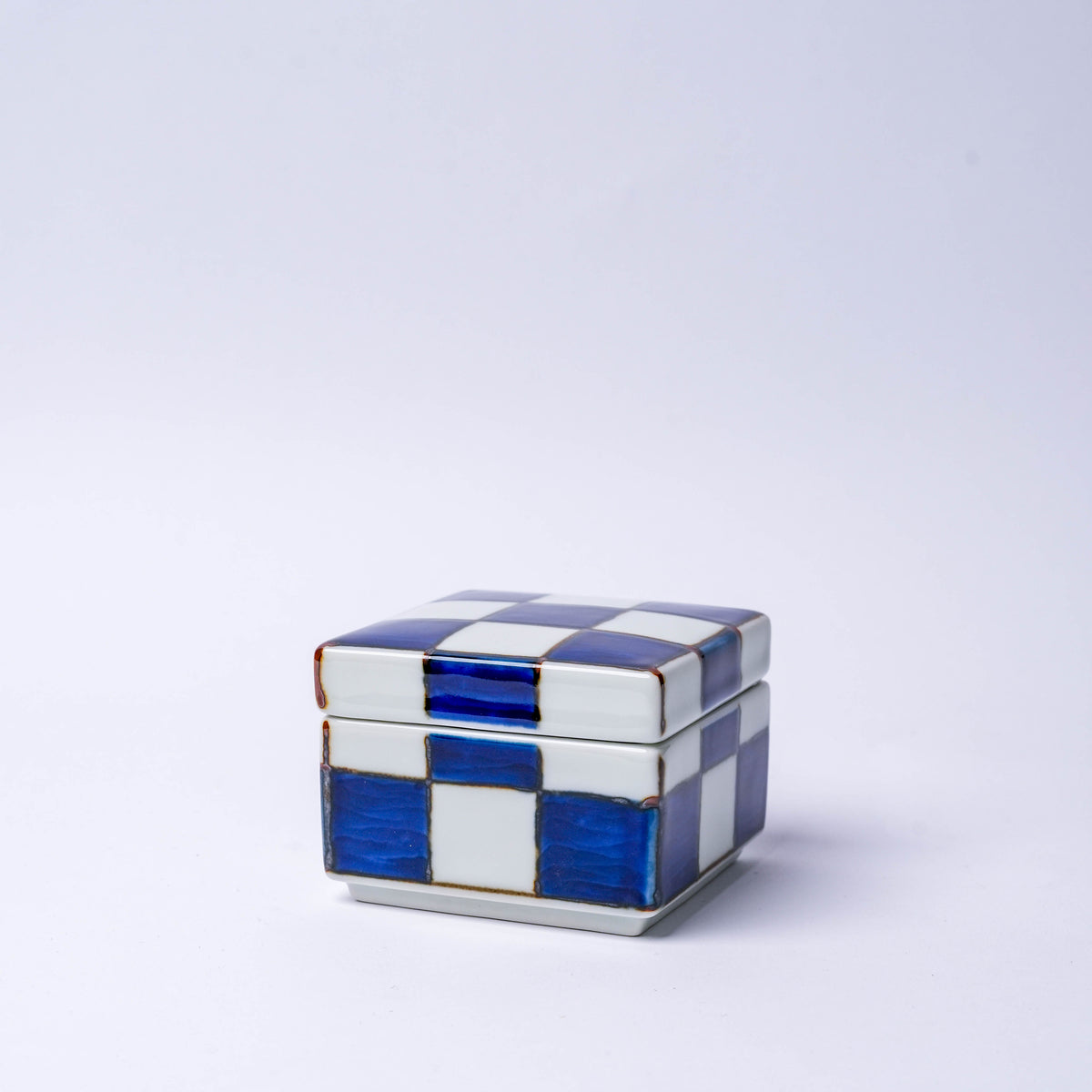 Side view of the porcelain checkerboard trinket box with blue and white pattern, highlighting its rectangular shape and decorative design