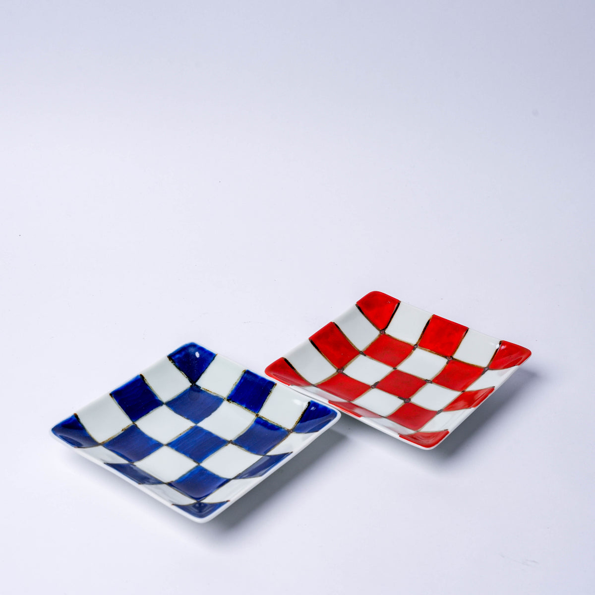 Colorful ceramic checkerboard square plates with red and blue patterns, traditional Japanese porcelain design, perfect for serving appetizers or sweets