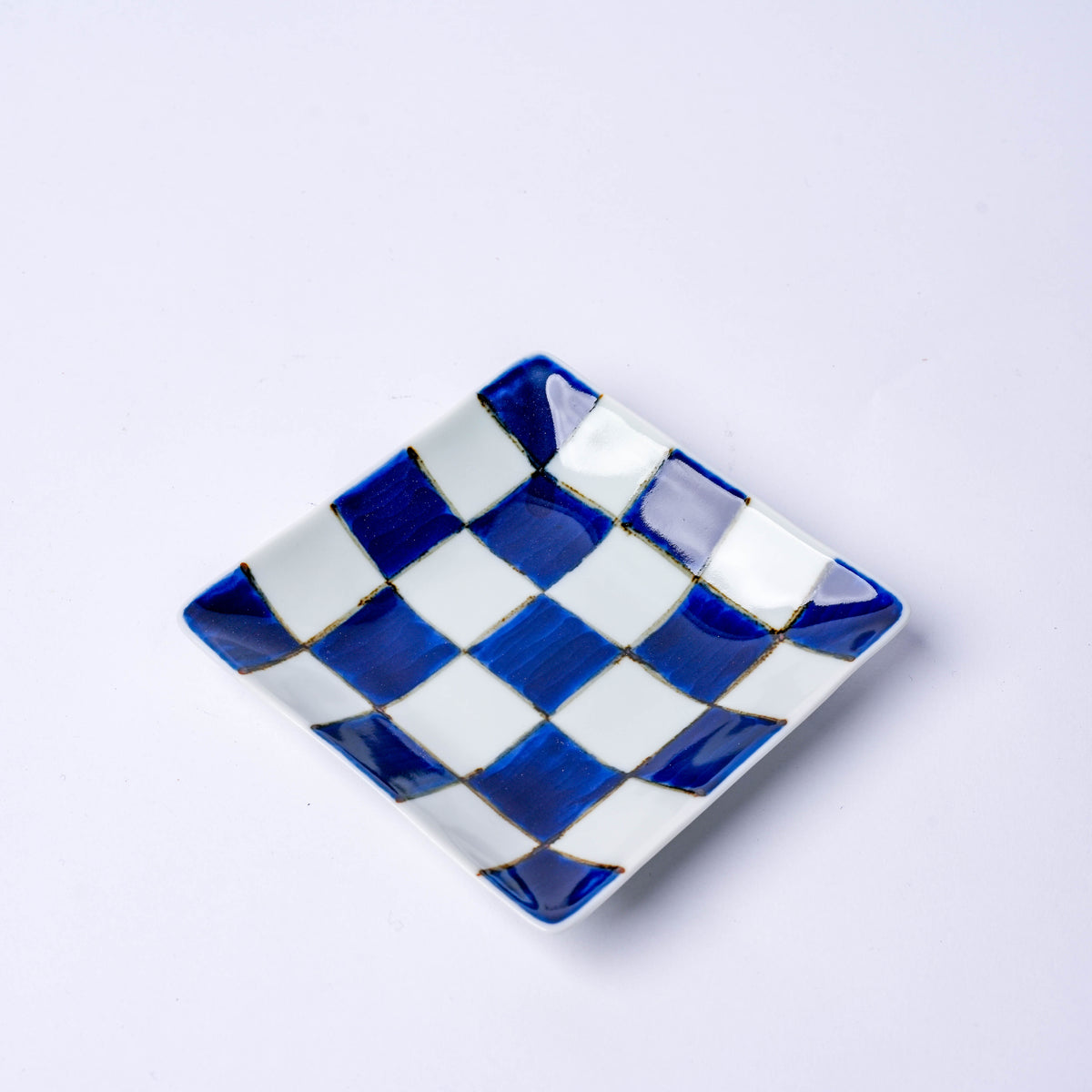 Close-up of a colorful Japanese porcelain square plate with red and blue checkered pattern, ideal for serving small dishes